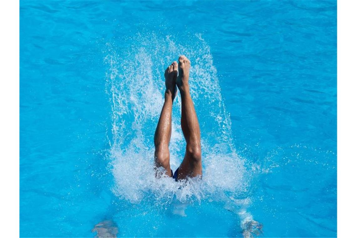 Ein junger Mann landet nach einem Sprung vom Drei-Meter-Brett im Wasser. Foto: Daniel Reinhardt/Archivbild
