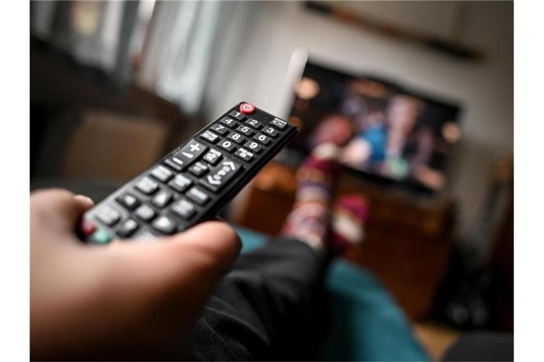 Ein junger Mann sitzt mit einer Fernbedienung vor dem Fernseher. Foto: Britta Pedersen/dpa-Zentralbild/dpa/Symbolbild