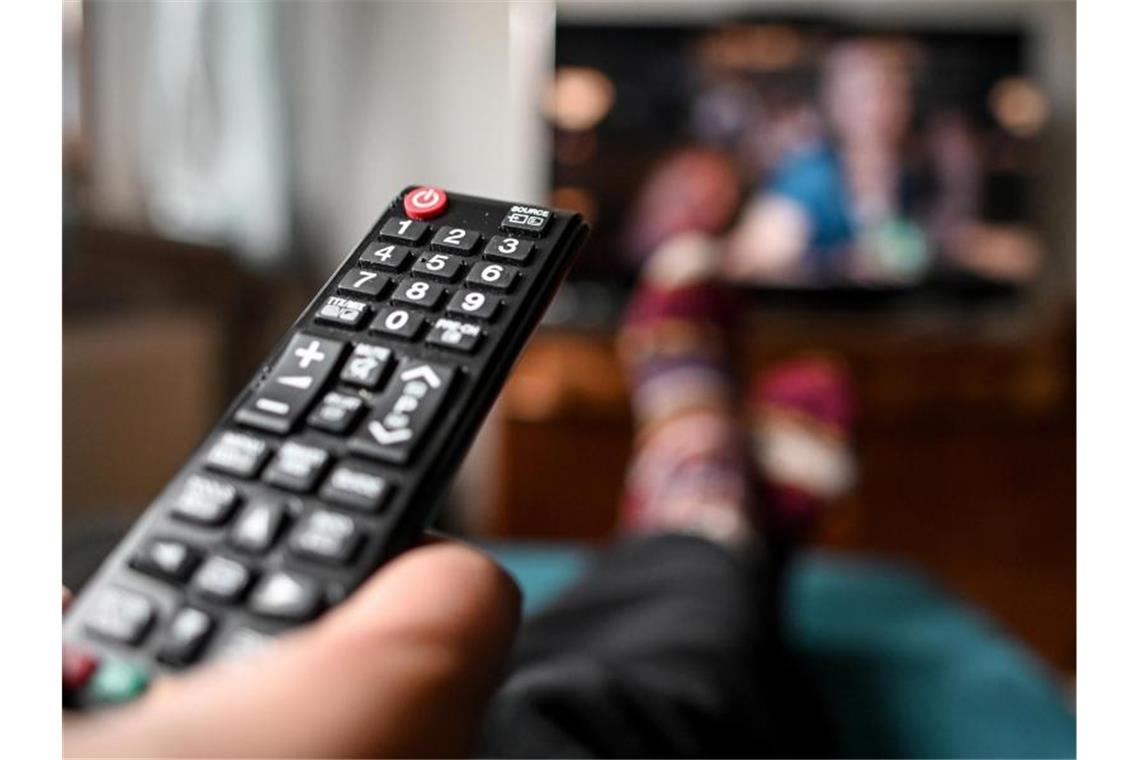 US-Streamingriese Roku kommt auf den deutschen Markt Ein junger Mann sitzt mit einer Fernbedienung vor dem Fernseher. Streaminggeräte in Deutschland bekommen von US-Riese Roku Konkurrenz. Foto: Britta Pedersen/dpa-Zentralbild/dpa