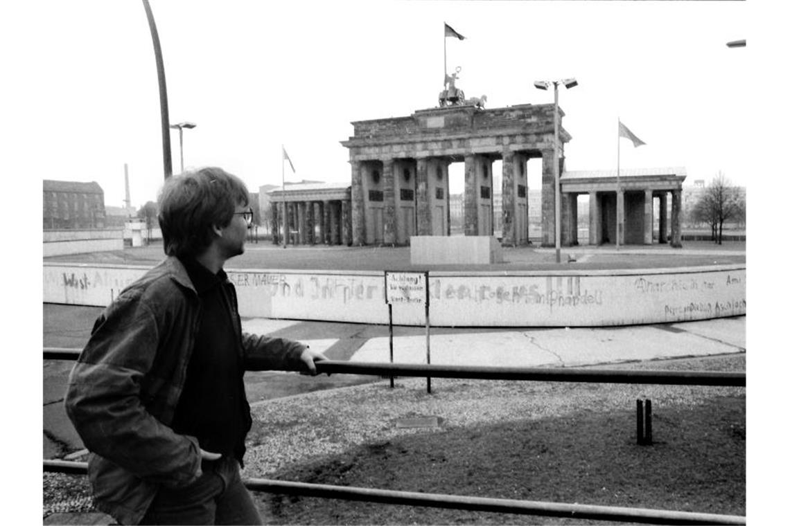 Ein junger Mann steht im April 1984 auf einem Aussichtspodest vor dem Brandenburger Tor und blickt über die Berliner Mauer nach Ost-Berlin. Foto: Wolfgang Kumm/dpa