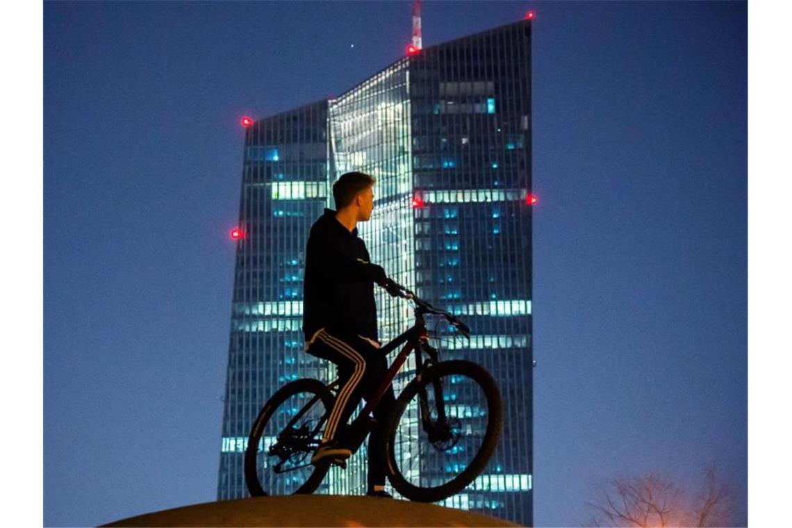 Ein junger Mann steht mit seinem Rad vor dem EZB-Tower. Europas Währungshüter stemmen sich mit Milliarden gegen die beispiellose Konjunkturkrise infolge der Corona-Pandemie. Foto: Andreas Arnold/dpa
