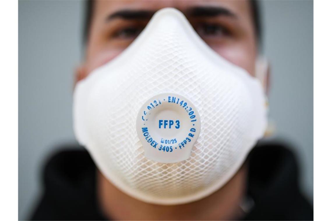 Ein junger Mann trägt eine Atemschutzmaske. Foto: Christoph Schmidt/dpa/Symbolbild