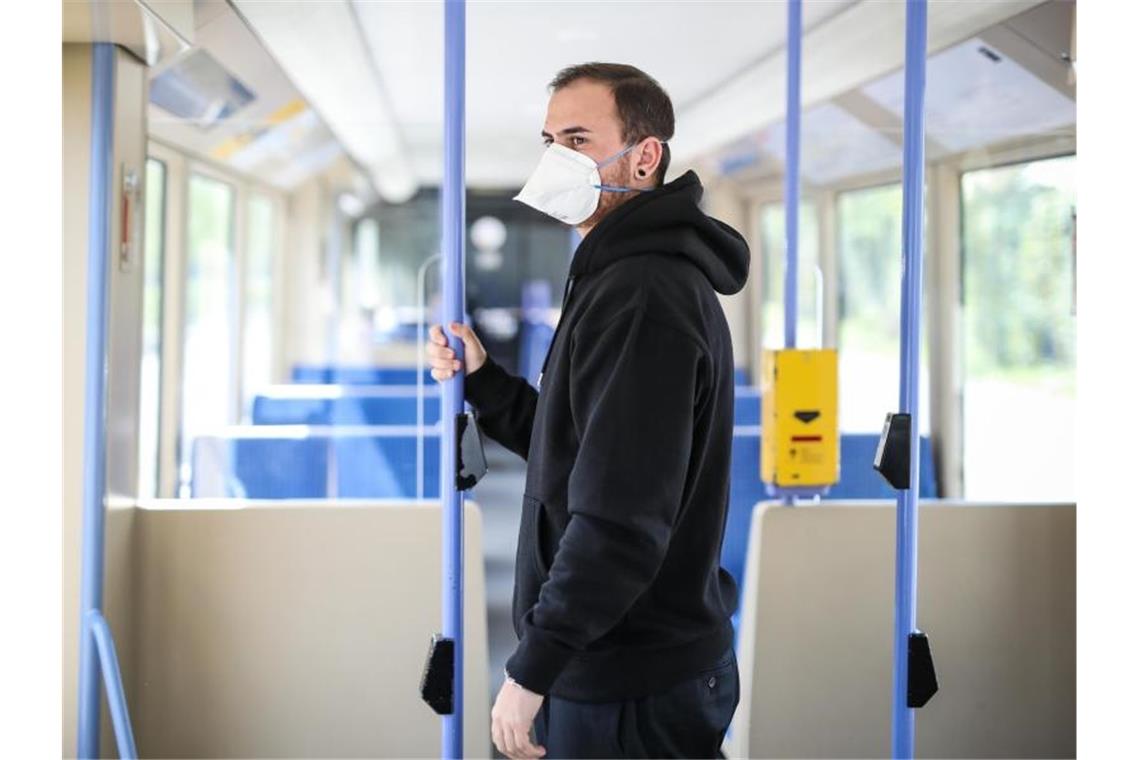 Ein junger Mann trägt in einer Stadtbahn eine Atemschutzmaske. Foto: Christoph Schmidt/dpa/Symbolbild