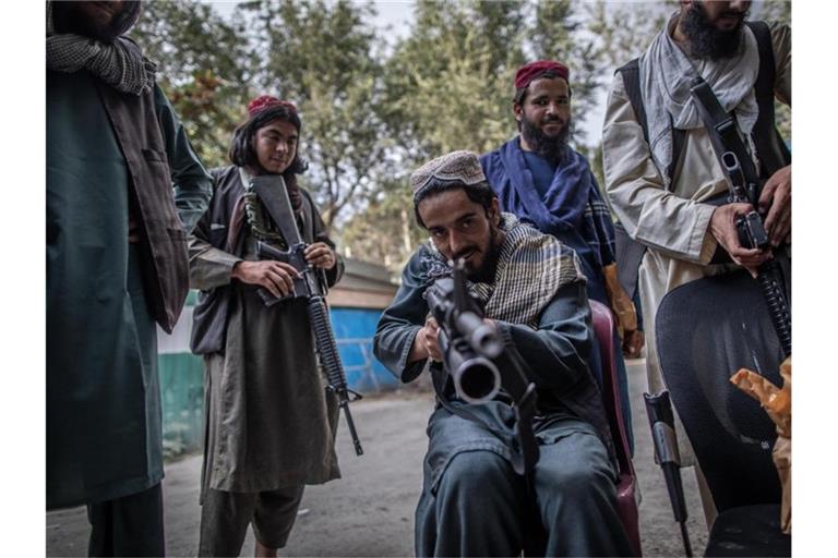 Ein junger Taliban-Kämpfer zielt zum Spaß mit seinem Gewehr in Richtung Fotograf, während er vor einer Polizeistation in Kabul Wache hält. Foto: Oliver Weiken/dpa