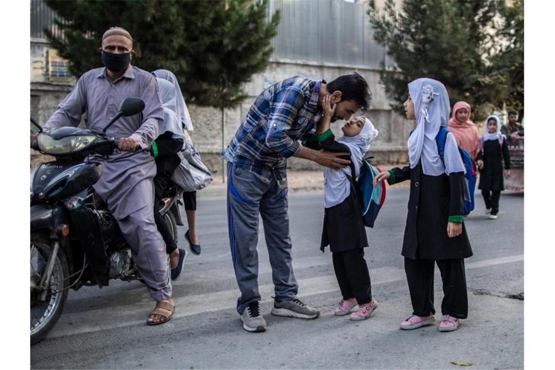 Ein junges afghanisches Mädchen gibt ihrem Vater einen Kuss, bevor sie eine Grundschule in Kabul besucht. (Archivbild). Foto: Oliver Weiken/dpa