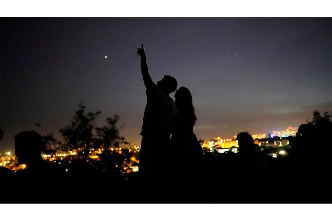Bilder des Tages Ein junges Paar steht auf einer Mauer und betrachtet den Himmel an einem Aussichtspunkt über Lissabon während eines landesweiten Stromausfalls.