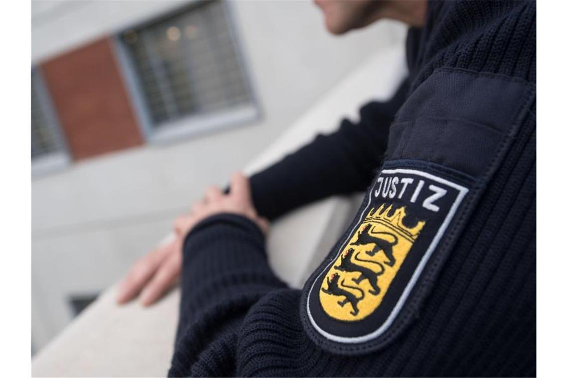 Demonstranten zünden Feuerwerkskörper vor JVA Stammheim Ein Justizbeamter steht in einem Hof eines neuen Haftgebäudes der JVA Stammheim. Foto: Marijan Murat/dpa/Archivbild