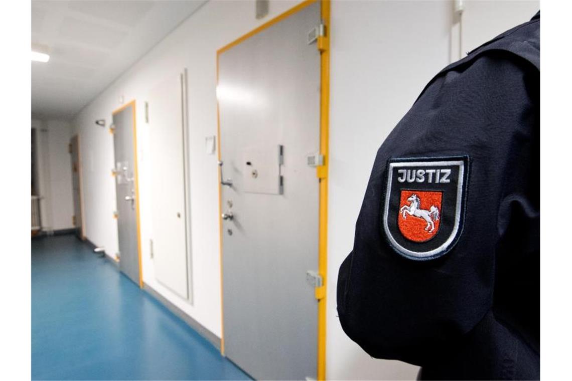 Ein Justizbeamter steht neben Zellen von Gefangenen. Foto: Julian Stratenschulte/dpa/Archiv