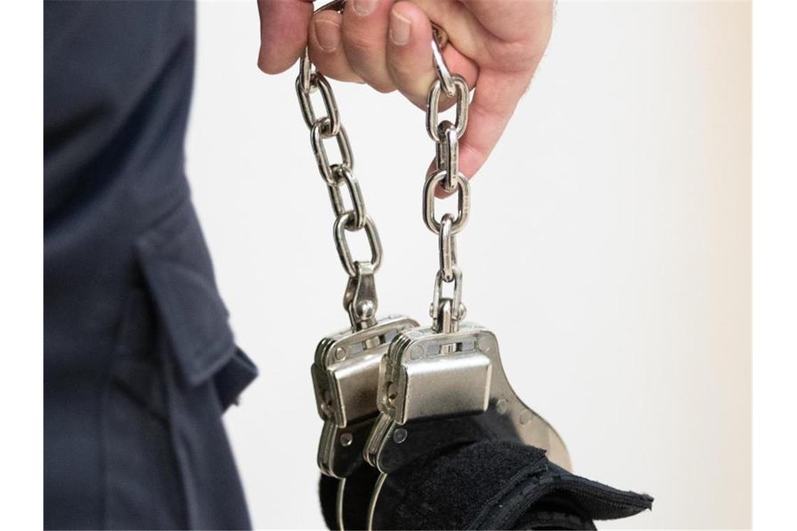 Ein Justizbeamter trägt Handschellen. Foto: Friso Gentsch/dpa/Symbolbild