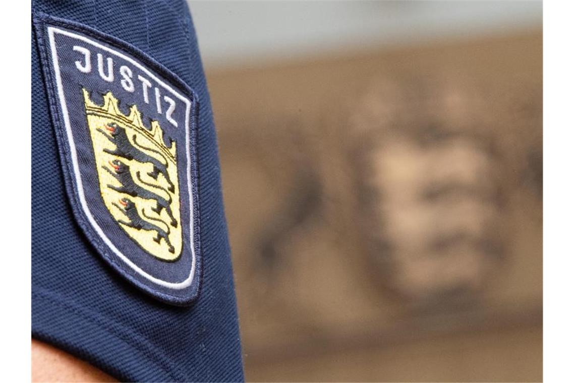 IS-Heimkehrerin distanziert sich von Terrororganisation Ein Justizmitarbeiter steht im Oberlandesgericht Stuttgart vor dem Wappen von Baden-Württemberg. Foto: Sebastian Gollnow/Archivbild