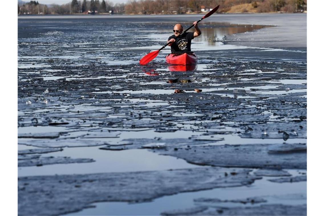 Ein Kajakfahrer paddelt zwischen losen Eisschollen über den Staffelsee in Oberbayern. Foto: Angelika Warmuth/dpa