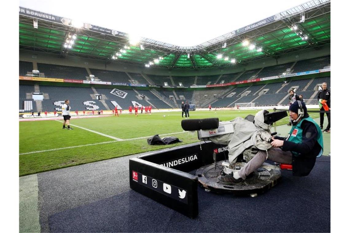 Ein Kameramann filmt das Aufwärmen der Mannschaften im zuschauerfreien Stadion Borussia Park. Foto: Roland Weihrauch/dpa