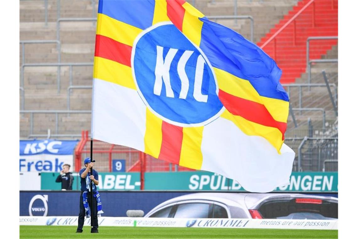 Ein Karlsruher Fan schwenkt eine Fahne mit der Aufschrift "KSC". Foto: Uwe Anspach/Archivbild