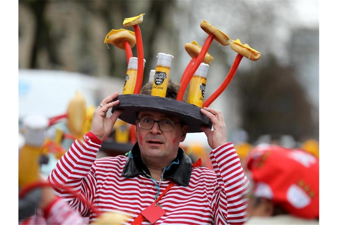 Sturmböen verhindern Karnevalsumzüge Ein Karnevalist hält in Köln sein Kostüm fest. Foto: Oliver Berg/dpa