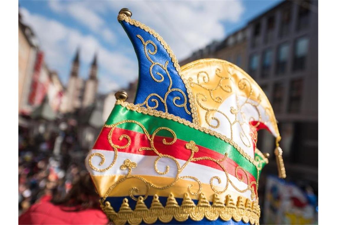 Digital und „to go“: Narren stimmen sich auf Fastnacht ein Ein Karnevalist trägt beim Faschingsumzug eine bunte Narrenkappe. Foto: Daniel Peter/dpa/Archivbild