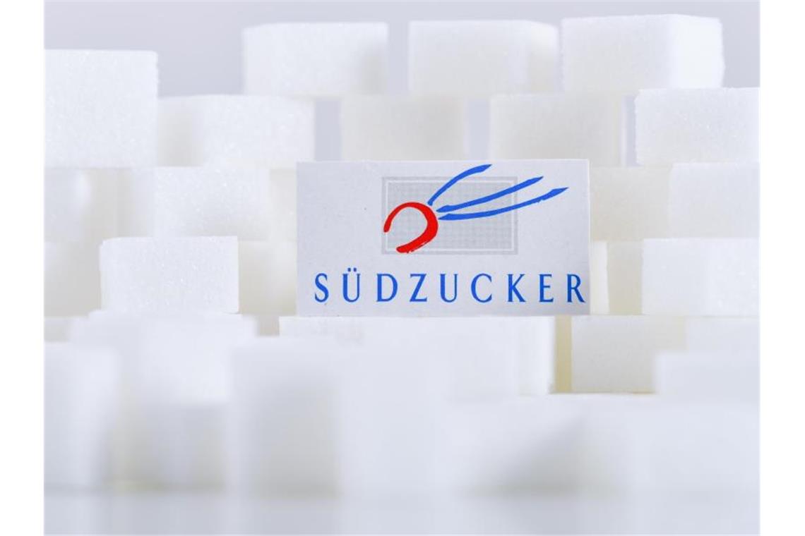 Ein Kartonausschnitt mit dem Schriftzug von Südzucker liegt auf Zuckerwürfeln. Foto: Uwe Anspach/dpa