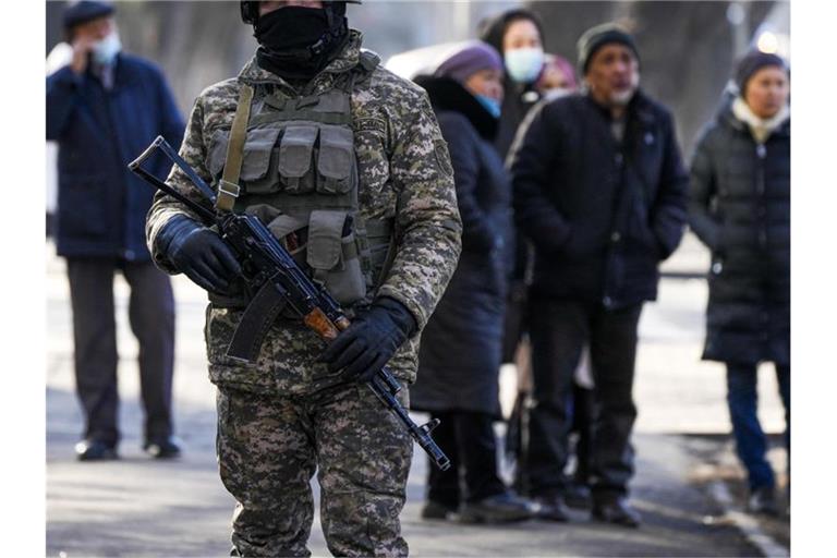 Ein kasachischer Soldat patrouilliert in Almaty nahe einer Polizeistation. Hinter ihm versammeln sich Angehörige von Personen, die nach den Protesten gegen die Regierung verhaftet wurden. Foto: Sergei Grits/AP/dpa
