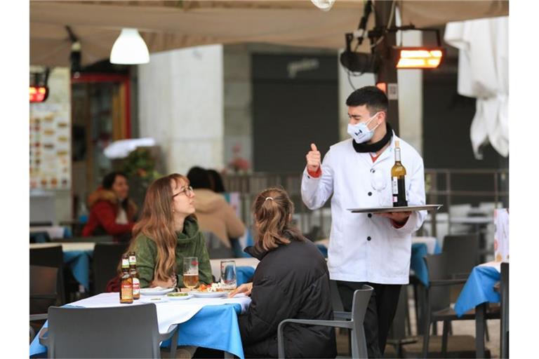 Ein Kellner bedient zwei Kundinnen auf der Terrasse einer Bar im Zentrum von Madrid. Foto: Tamara Rozas/Europapress/dpa