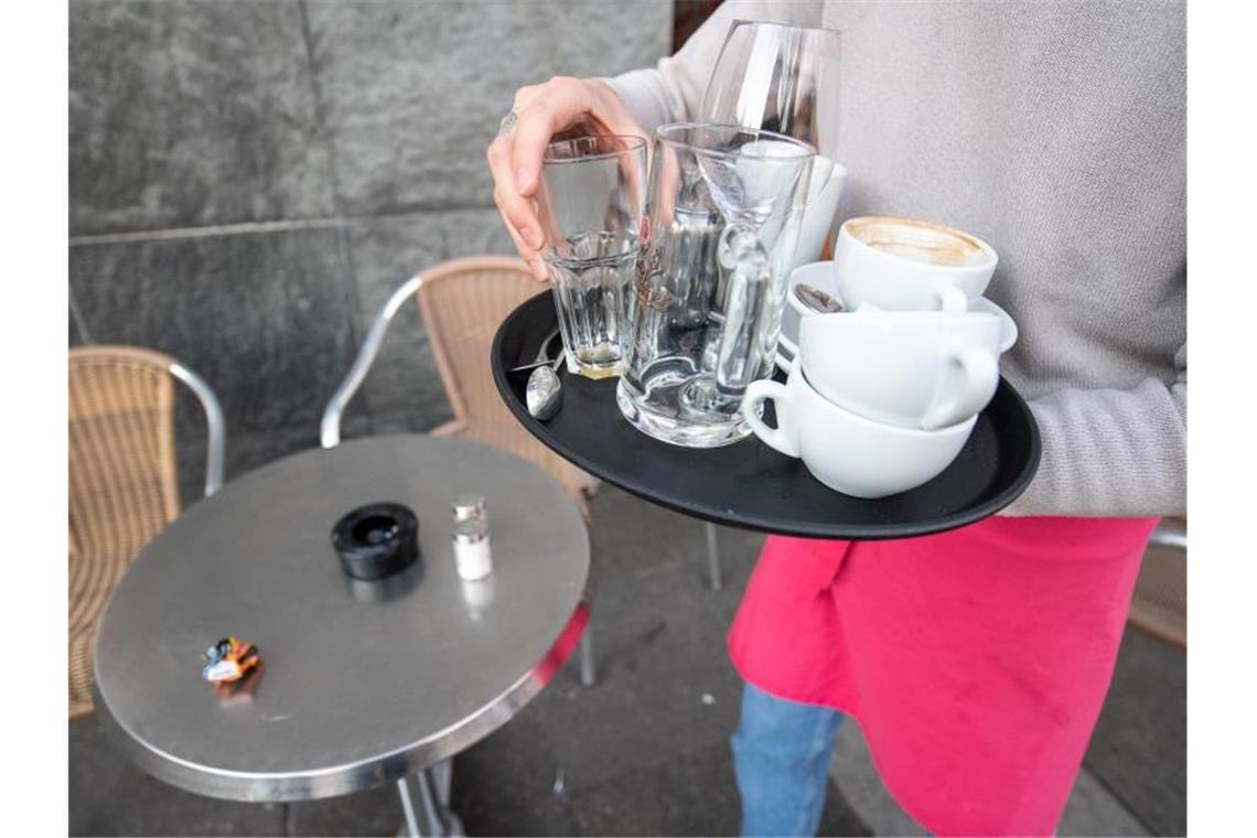 Corona als Betriebsrisiko? - Urteil zu Minijobbern erwartet Ein Kellner räumt einen Tisch in einem Restaurant ab. Ob Minijobber auf Bezahlung pochen können, wenn ihre Arbeit während der Lockdownphasen in der Corona-Pandemie nicht gebraucht wurde, will das Bundesarbeitsgericht jetzt grundsätzlich klären. Foto: Sebastian Gollnow/dpa