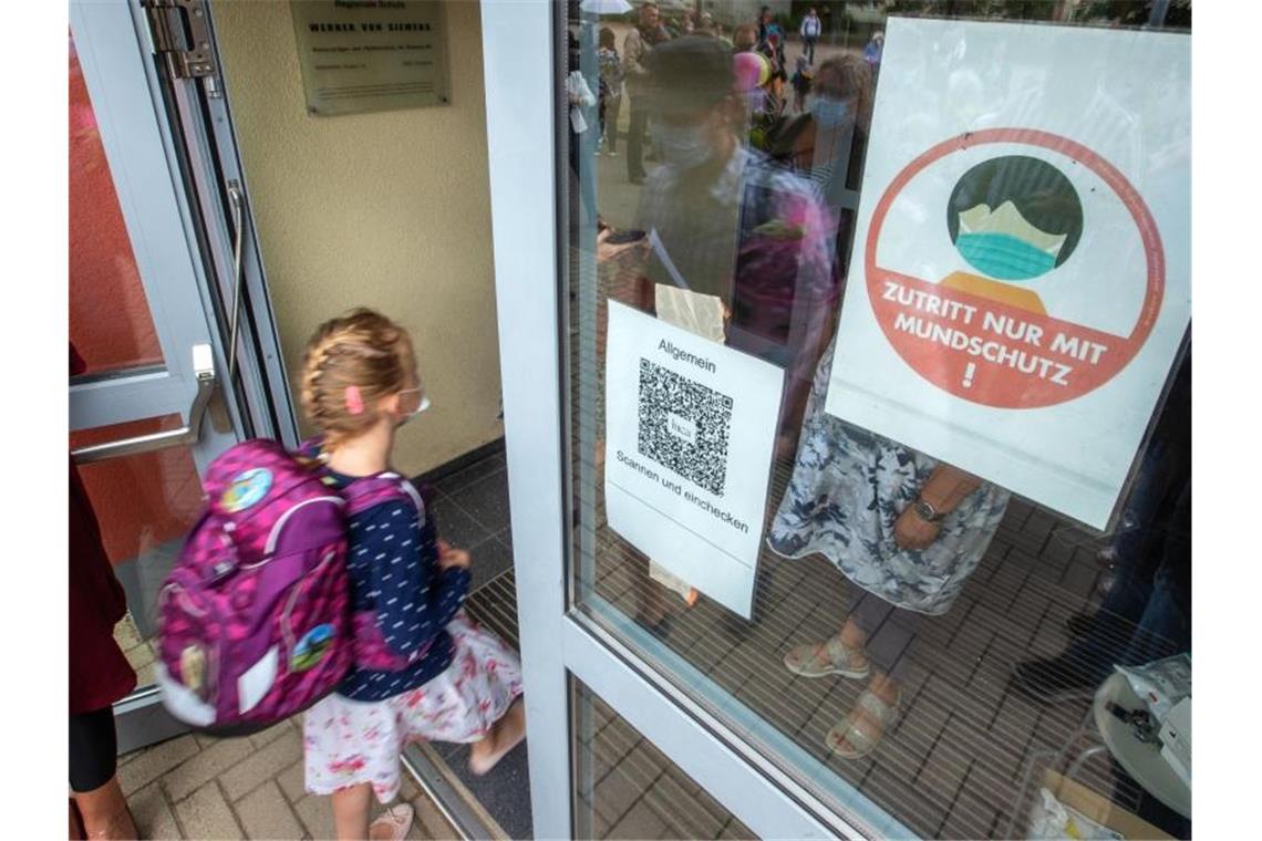 Ein Kind geht mit Maske in eine Schule. Das Robert Koch-Institut (RKI) registriert in einzelnen Regionen Deutschlands besonders viele Corona-Ansteckungen bei Kindern und Jugendlichen. Foto: Jens Büttner/dpa-Zentralbild/dpa