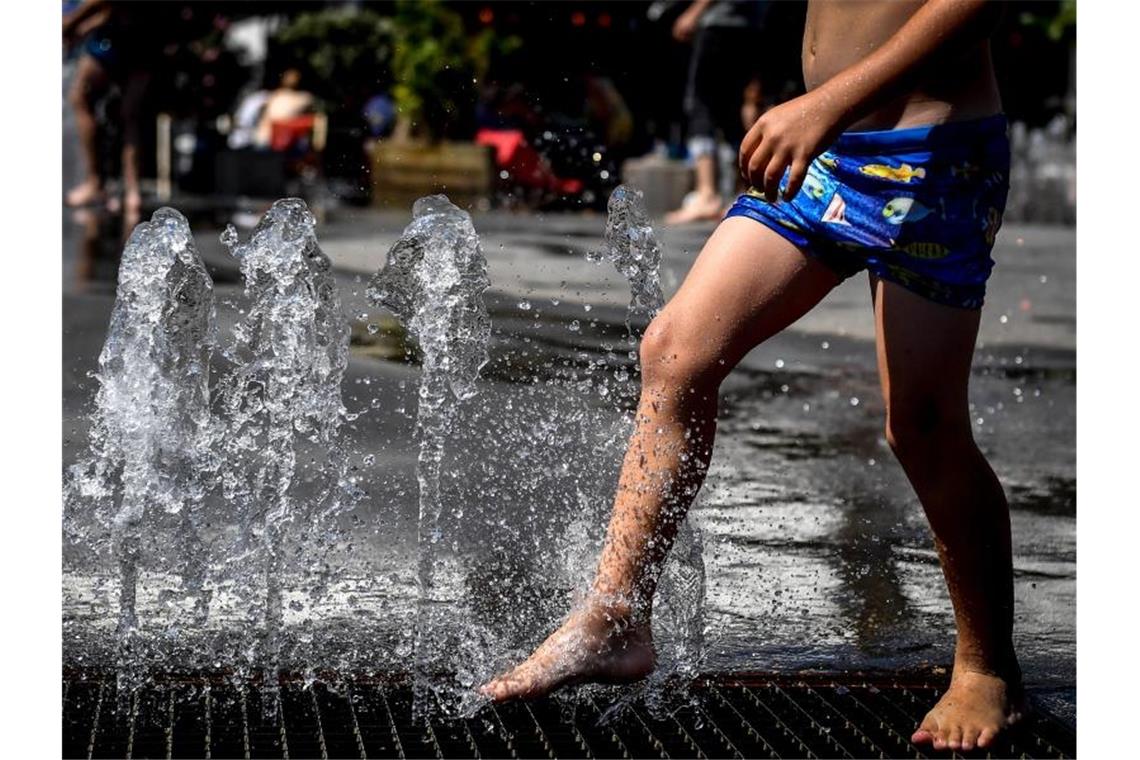 Ein Kind kühlt sich in einem Springbrunnen ab. In Deutschland wird es heiß. Foto: Dirk Waem/BELGA