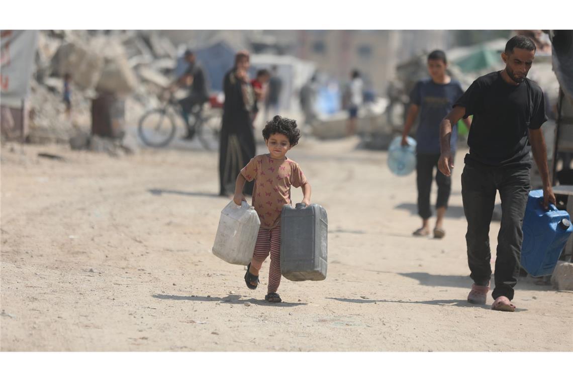 Bilder des Tages Ein Kind trägt Kanister, um sich in Gaza Wasser von einem Tankwagen zu holen.