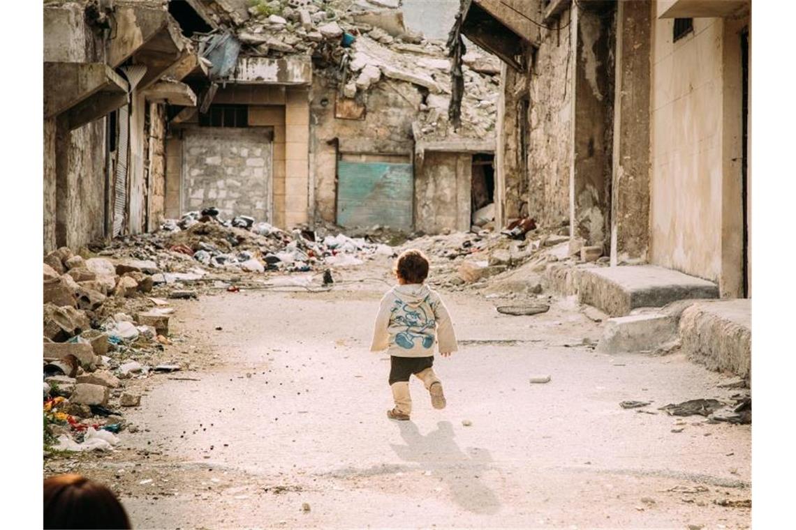 Ein kleiner Junge geht durch eine vom Bürgerkrieg zerstörte Straße in der syrischen Metropole Aleppo. Foto: Alea Horst/SOS-Kinderdörfer weltweit/dpa