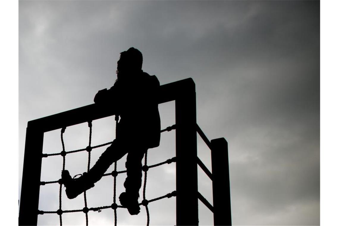 Ein kleines Mädchen spielt an einem Klettergerüst vor dunklem Himmel. Foto: Julian Stratenschulte/dpa/Symbolbild