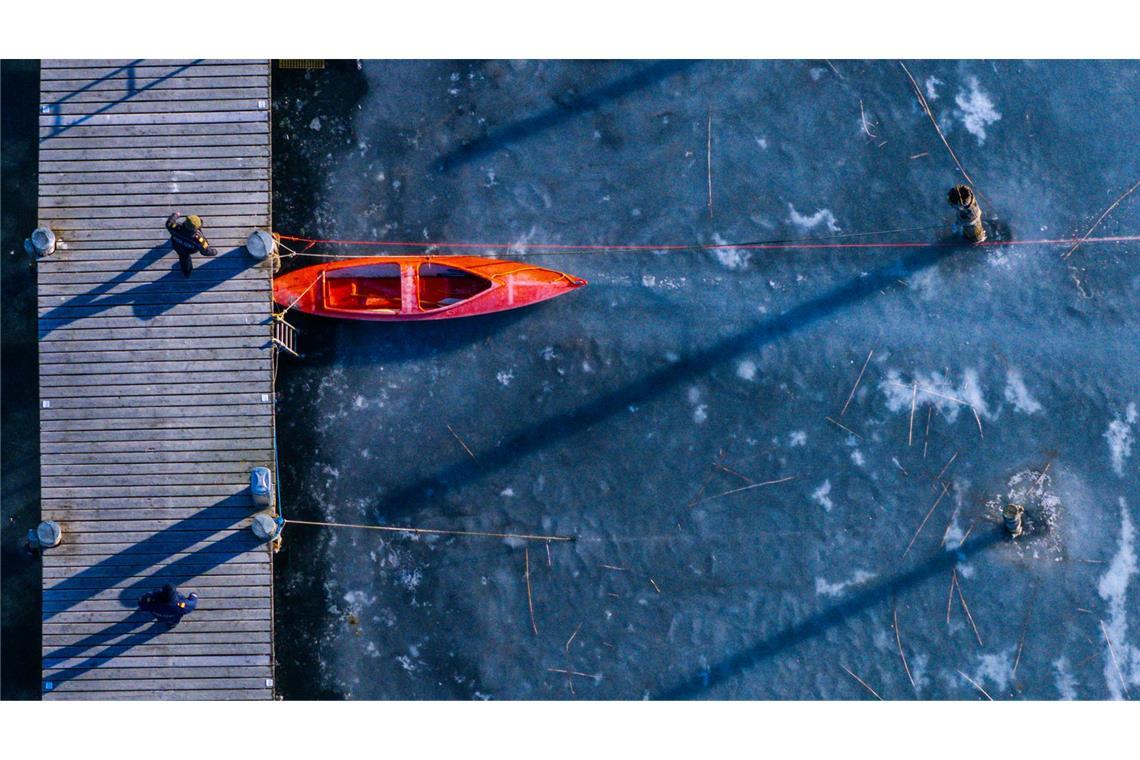 Ein kleines Paddelboot liegt am Anleger im Hafen an der Wismarbucht zwischen der Insel Poel und der Ostsee auf dem Eis.