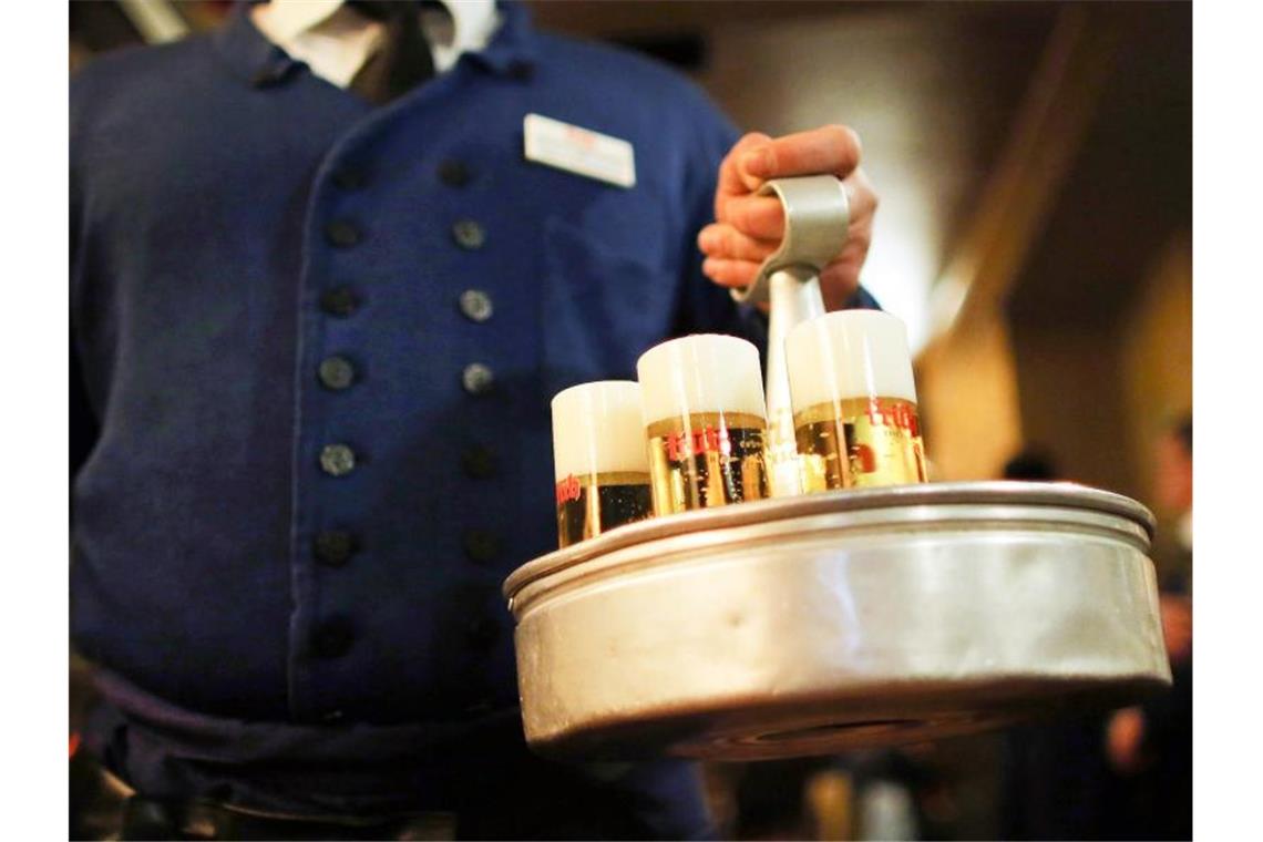 Ein Köbes (Kellner) serviert im Brauhaus Früh am Kölner Dom Kölsch-Bier. Foto: Oliver Berg/dpa