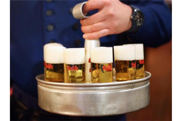 Ein Köbes (Kellner) trägt Kölsch-Bier aus. Das Oberlandesgericht Düsseldorf hat über die Einsprüche von drei Kölsch-Brauereien gegen Bierkartell-Bußgelder entschieden. Foto: picture alliance / dpa