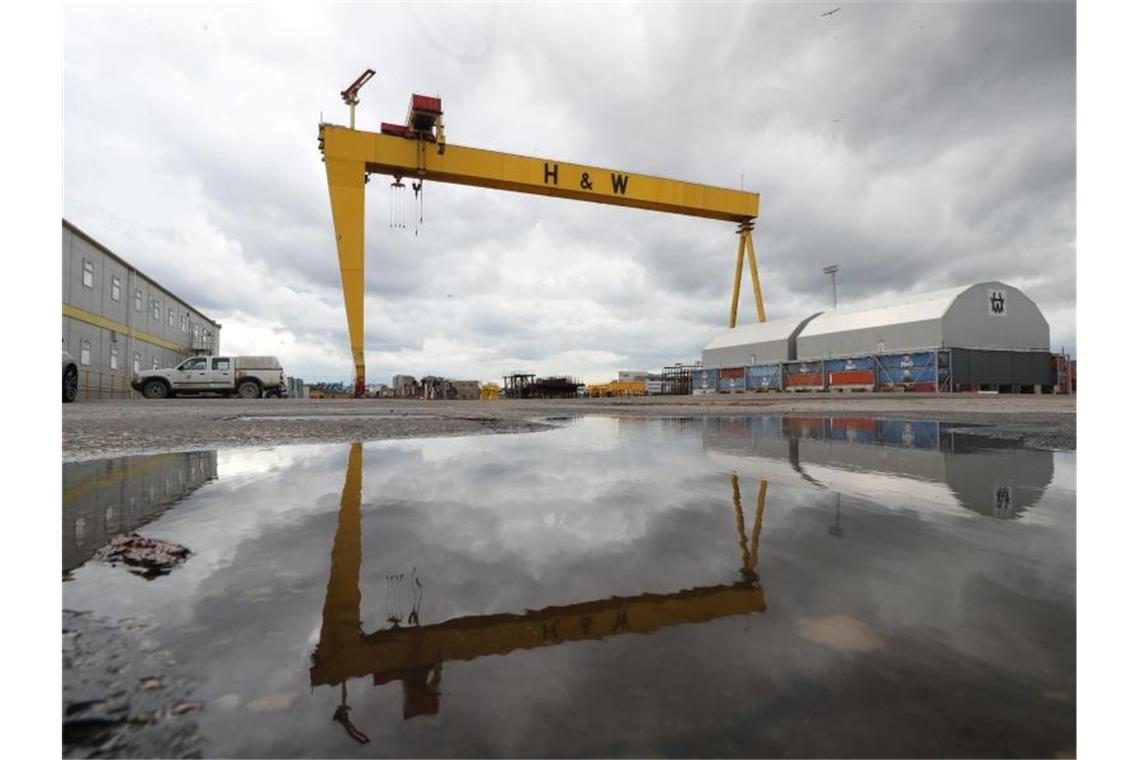 Ein Kran der Werft Harland & Wolff spiegelt sich auf dem Werksgelände in Belfast in einer Wasserlache. Foto: Liam Mcburney/PA Wire