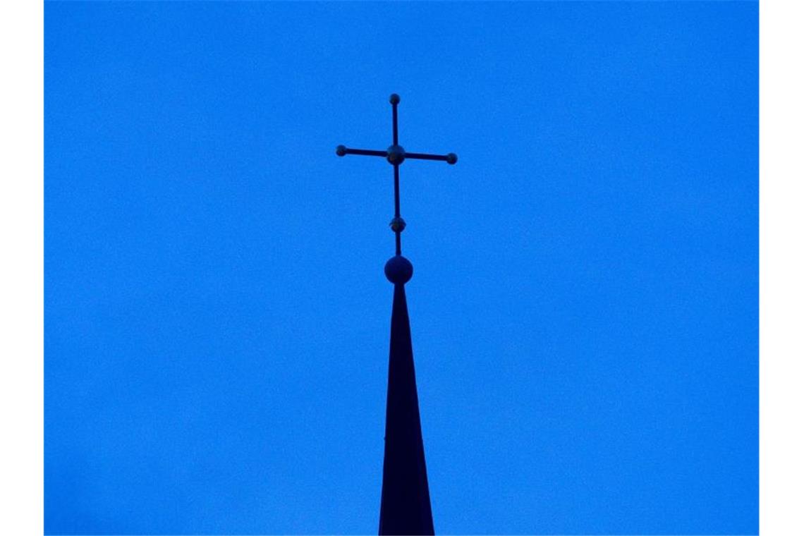 „O du fröhliche“ erklingt online: Mitsing-Aktion der Kirche Ein Kreuz ist auf einer Kirchturmspitze zu sehen. Foto: Friso Gentsch/dpa/Symbolbild
