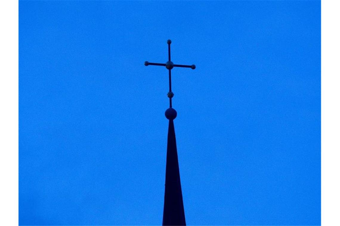 So viele Kirchenaustritte wie nie zuvor im Südwesten Ein Kreuz ist auf einer Kirchturmspitze zu sehen. Foto: Friso Gentsch/dpa/Symbolbild