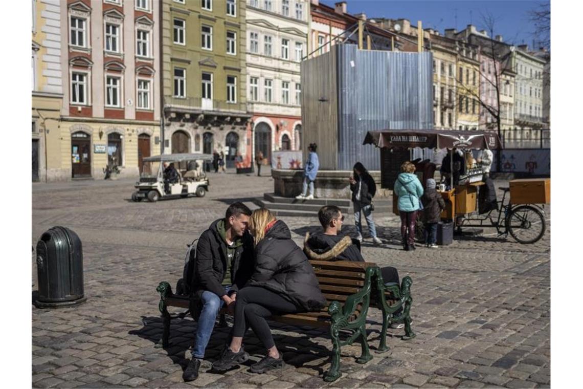 Das friedliche Leben im angegriffenen Land Ein küssendes Paar sitzt in der Innenstadt von Lwiw auf einer Bank. Foto: Bernat Armangue/AP/dpa