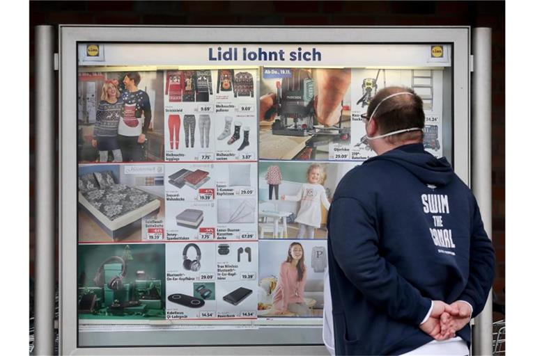 Ein Kunde einer Lidl-Filiale informiert sich an einer Werbetafel über die Sonderangebote. Foto: Roland Weihrauch/dpa