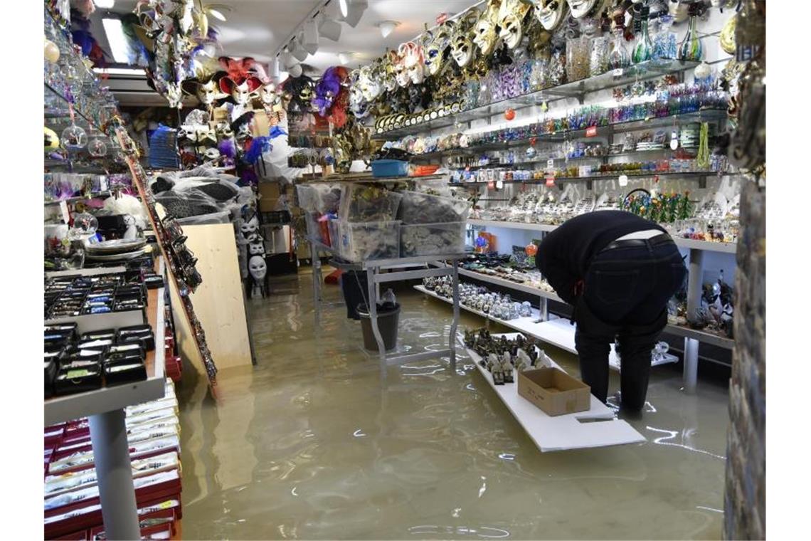 Ein Ladenbesitzer überprüft in seinem überfluteten Souvenirgeschäft die Schäden. Foto: Luigi Costantini/AP/dpa