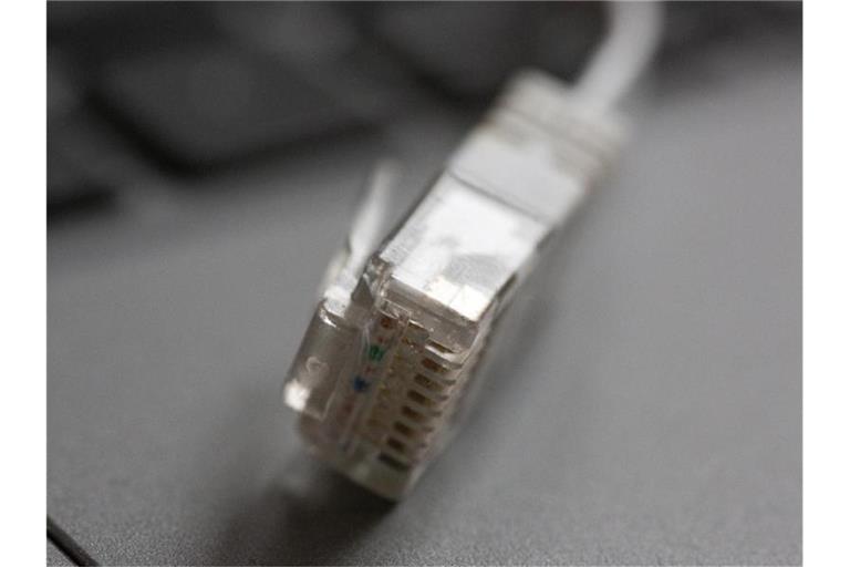 Ein LAN-Kabel liegt auf einem Computerlaptop. Foto: Fernando Gutierrez-Juarez/dpa-Zentralbild/dpa/Symbolbild