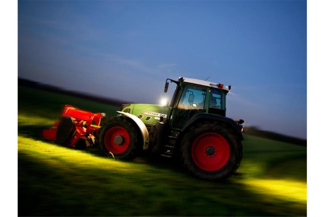 Ein Landwirt mäht mit einem Traktor eine Wiese. Foto: picture alliance / dpa/Symbolbild
