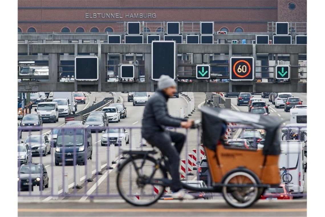 Ein Lastenrad-Fahrer fährt in Hamburg über die A7, auf der sich vor dem Elbtunnel der Verkehr staut. Foto: Georg Wendt/dpa