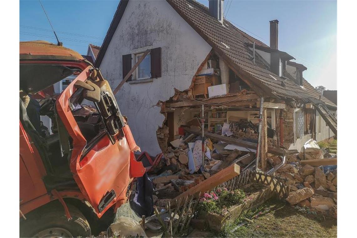 Lastwagen fährt gegen Haus: Fahrer lebensgefährlich verletzt Ein Lastwagen mit zerbeulter Tür steht vor einem Wohnhaus. Foto: Markus Brandhuber/Ostalb Network