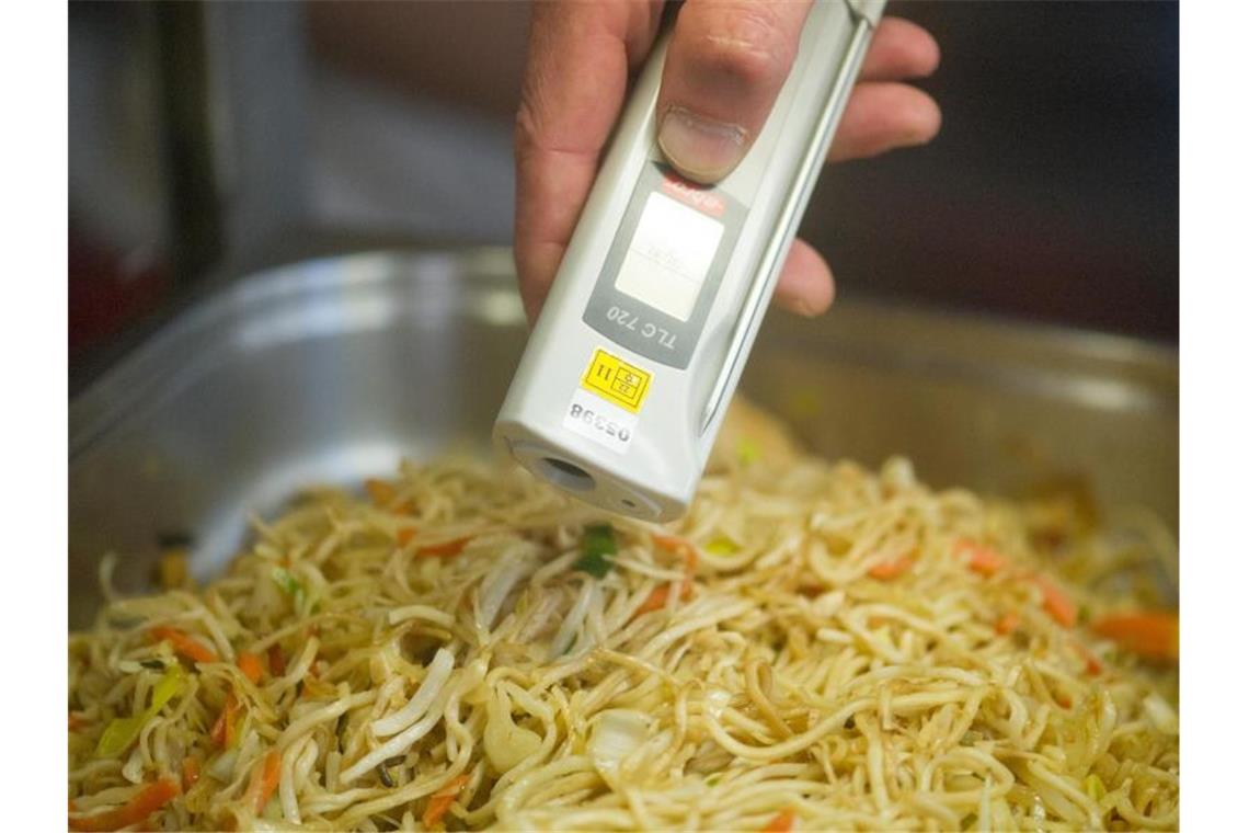 Ein Lebensmittelkontrolleur überprüft bei einer Betriebskontrolle die Temperatur von chinesischen Nudeln. Foto: Uwe Anspach/dpa