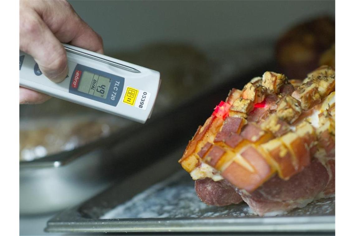 Ein Lebensmittelkontrolleur überprüft bei einer Betriebskontrolle die Temperatur einer Fleischware. Foto: Uwe Anspach/dpa/Archivbild