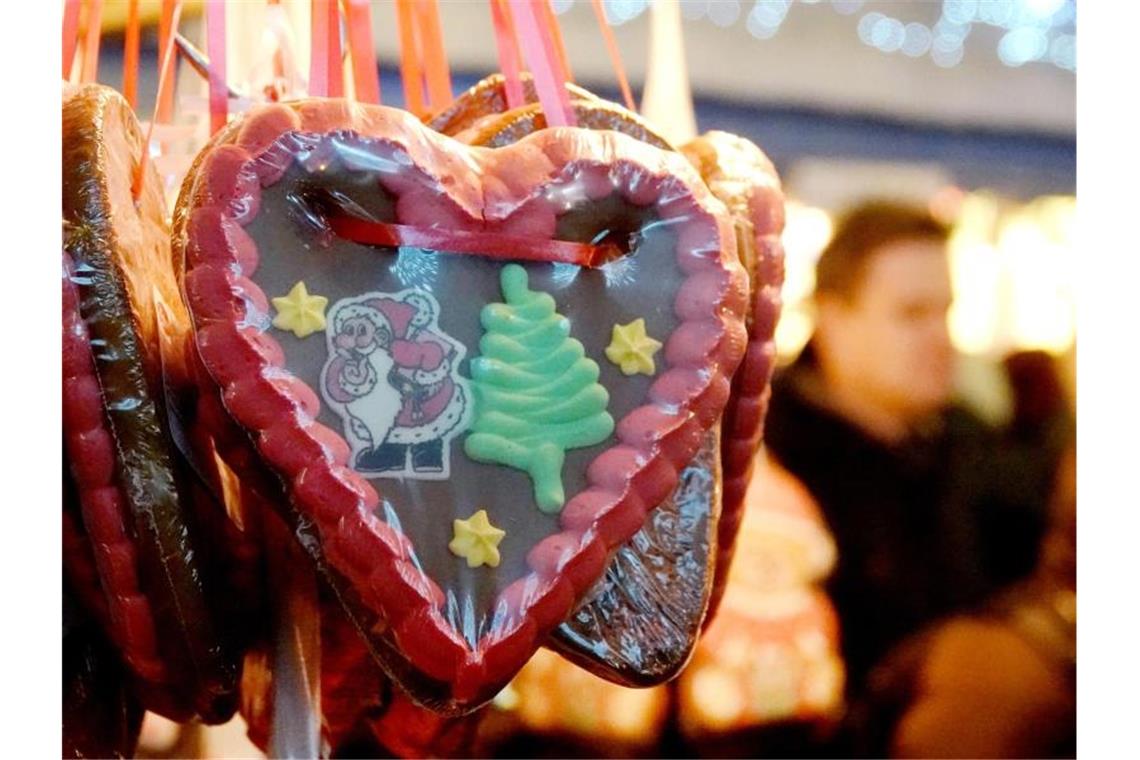 Ein Lebkuchenherz mit einem Tannenbaum und einem Weihnachstmann hängt an einem Stand auf einem Weihnachtsmarkt. Foto: David Schwarz/dpa/Archivbild