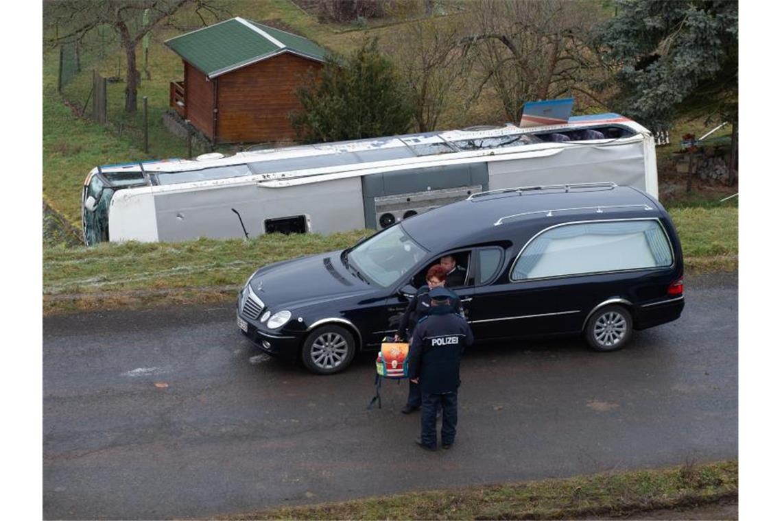 Zwei Kinder sterben bei schwerem Schulbusunfall in Thüringen Ein Leichenwagen fährt an dem verunglückten Schulbus vorbei. Zwei Kinder sind ums Leben gekommen. Foto: Swen Pförtner/dpa