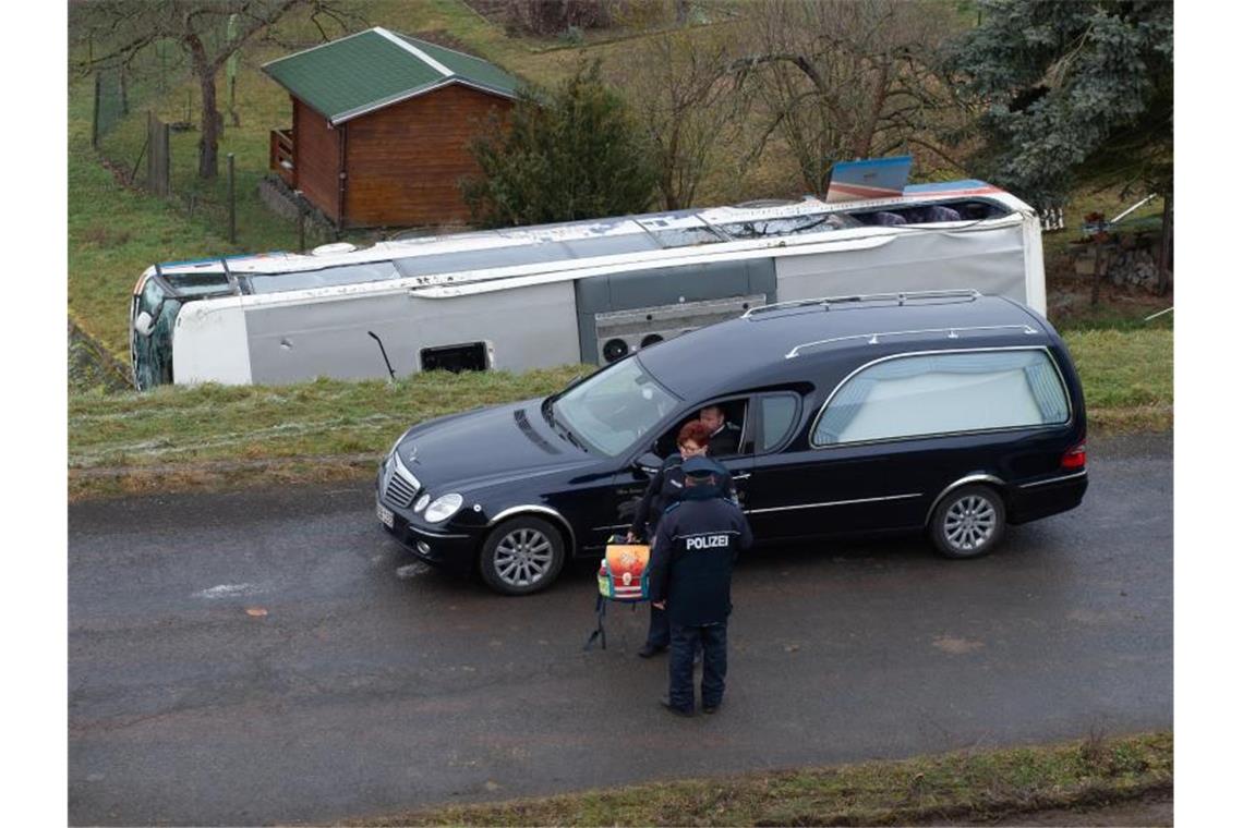 Ein Leichenwagen fährt an dem verunglückten Schulbus vorbei. Zwei Kinder sind ums Leben gekommen. Foto: Swen Pförtner/dpa