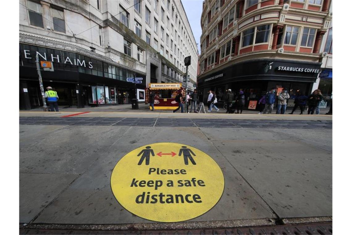 Ein Leitschild auf dem Bürgersteig weist in Manchester auf die Beachtung der Mindestabstände hin. Foto: Danny Lawson/PA Wire/dpa