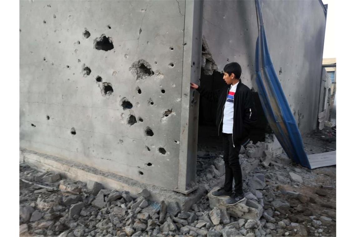 Libyen-Gipfel einigt sich auf Waffenembargo Ein libyscher Junge schaut auf ein zerstörtes Gebäude nach einem Luftangriff im Osten der Hauptstadt Tripolis. Foto: Hamza Turkia/XinHua/dpa