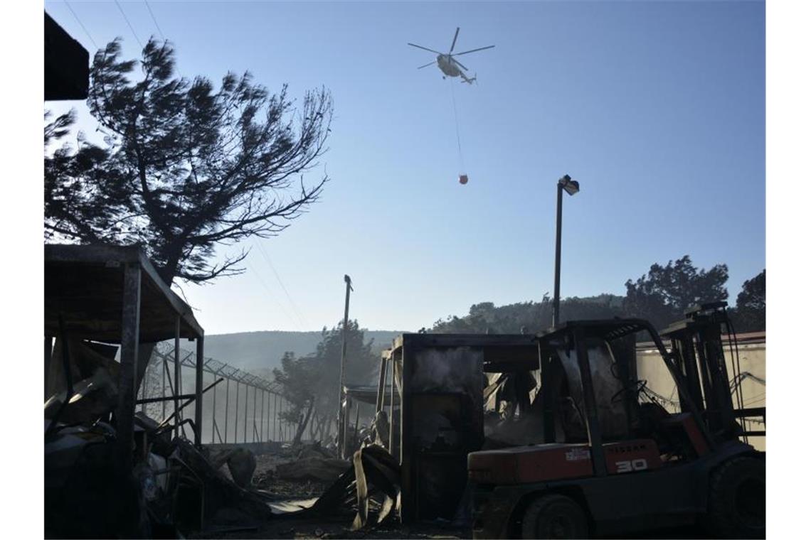 Ein Löschhubschrauber fliegt über dem Flüchtlingslager Moria. Die Behörden begannen noch in der Nacht, Menschen aus dem Lager zu bringen. Foto: Panagiotis Balaskas/AP/dpa