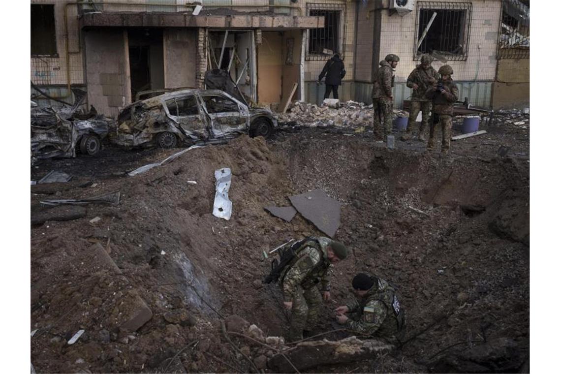 Ukraine wirft Russland Brutalität vor Ein mächtiger Krater vor einem Wohnhaus in der ukrainischen Hauptstadt Kiew. Bombenentschärfer suchen nach Blindgängern. Foto: Felipe Dana/AP/dpa